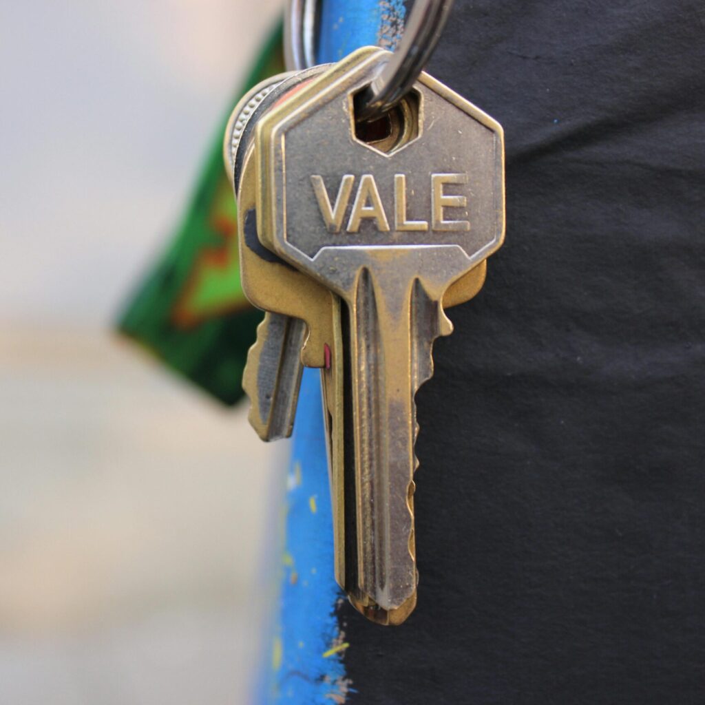 A detailed view of a metallic key with 'Vale' engraved on it, hanging against a blurred background.